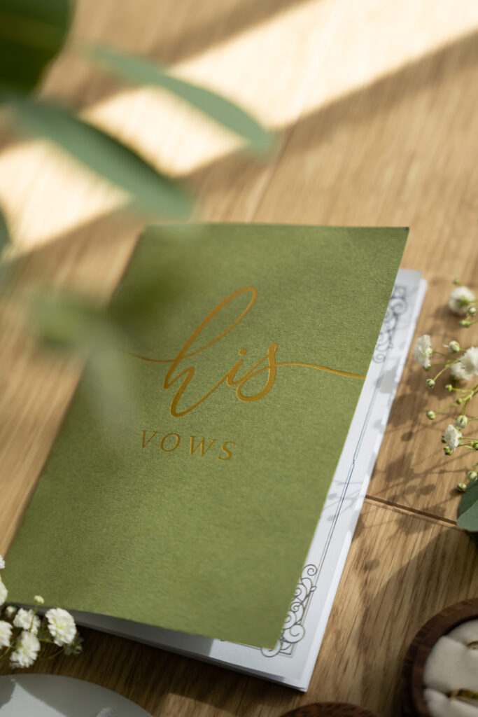 Detailaufnahme eines handgeschriebenen Ehegelübdes mit grünem Vows-Heft auf Holztisch – emotionale Hochzeitsfotografie in Niederösterreich

